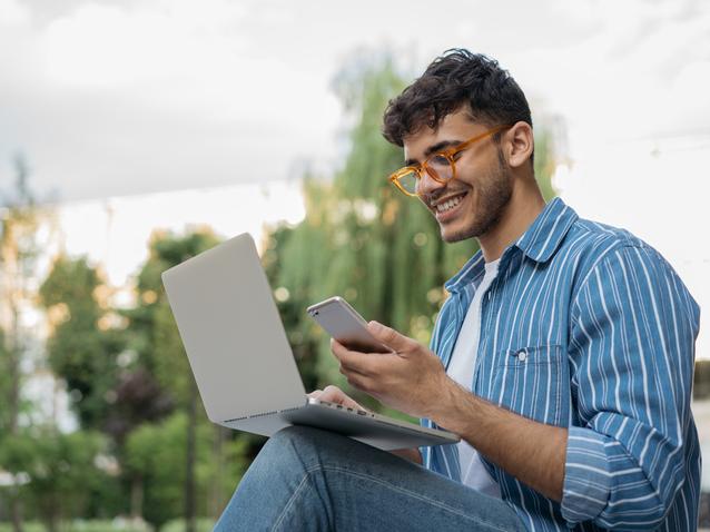 Young Indian man with phone and laptop