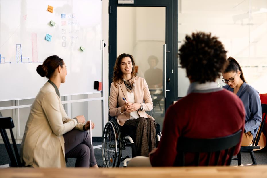A group of young researchers talking, one of them is in a wheelchair.