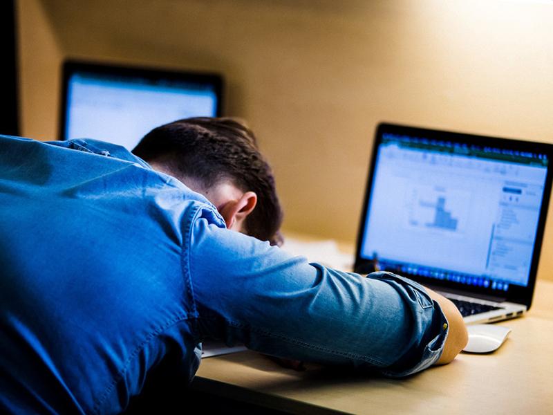 Depressed student hiding face on arms in front of laptop