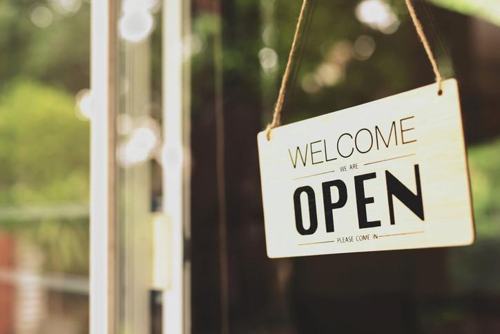 open welcome sign on a glass door