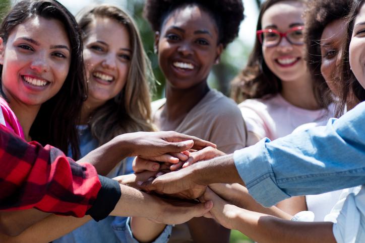 Group of female students joining hands in a show of unity