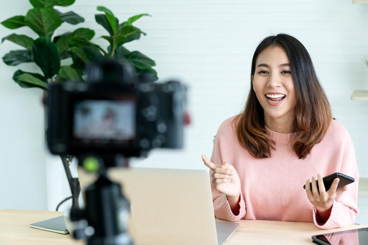 A young woman recording herself presenting on camera