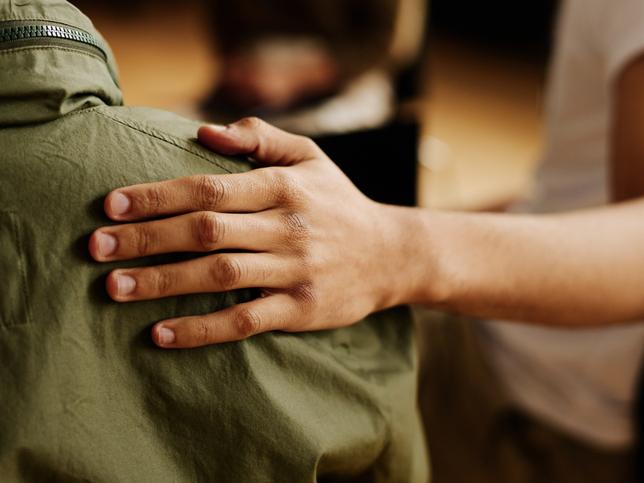 A hand resting on a shoulder in a display of support and care