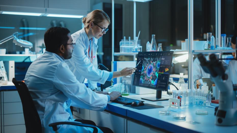 Two scientists in a lab looking at a laptop