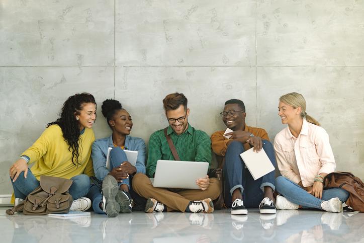 Students sitting together against a wall