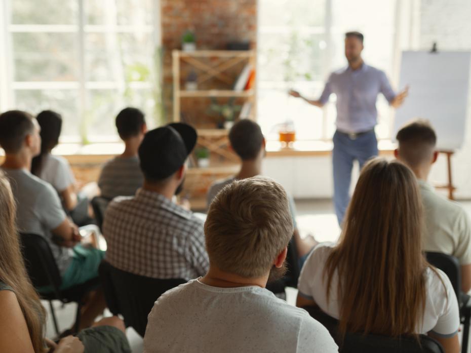 Lecturer standing before a class full of pupils giving a lecture