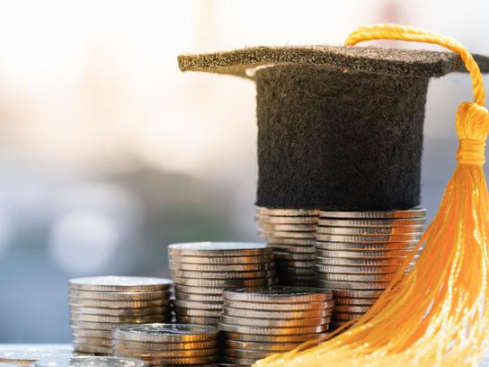 A motarboard sits atop a pile of coins