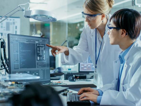 Two medical researchers looking at data on a screen