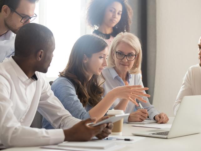 A group of people sitting round a laptop