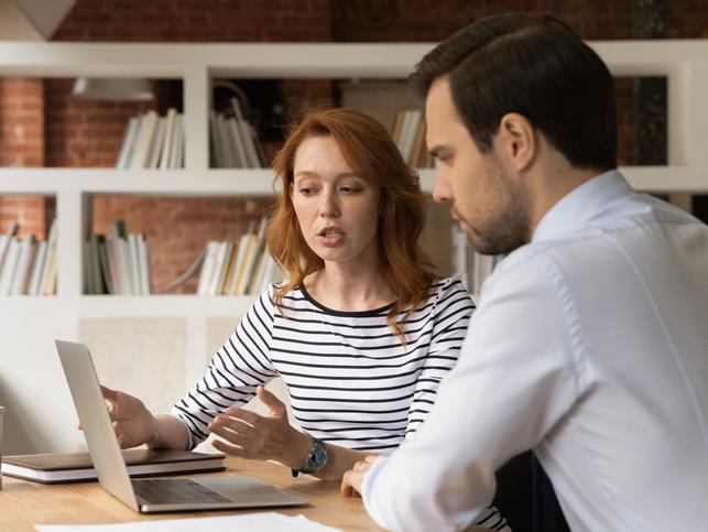 A man and woman discuss over a laptop