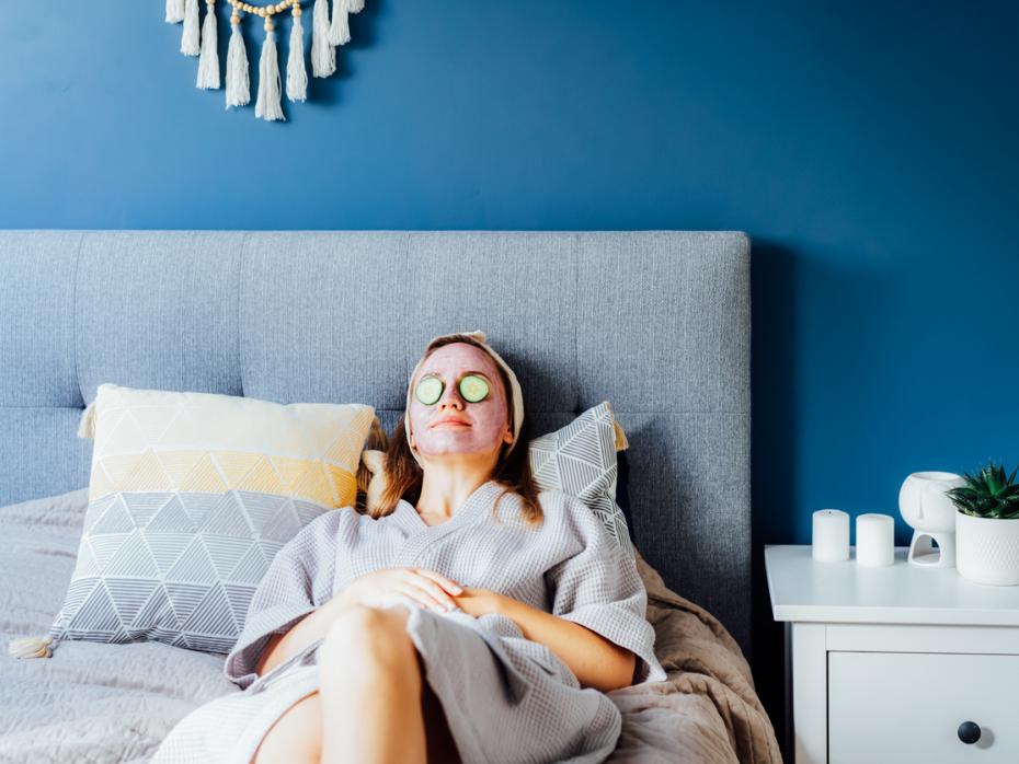 A woman with a hydrating face mask on relaxing in bed