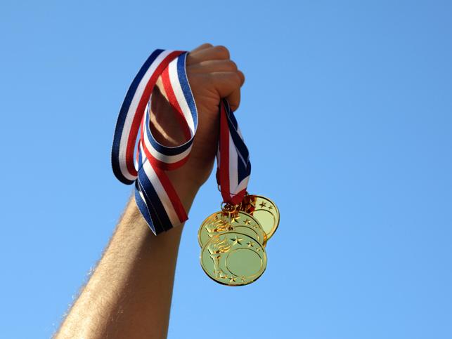 Hand holding three gold medals