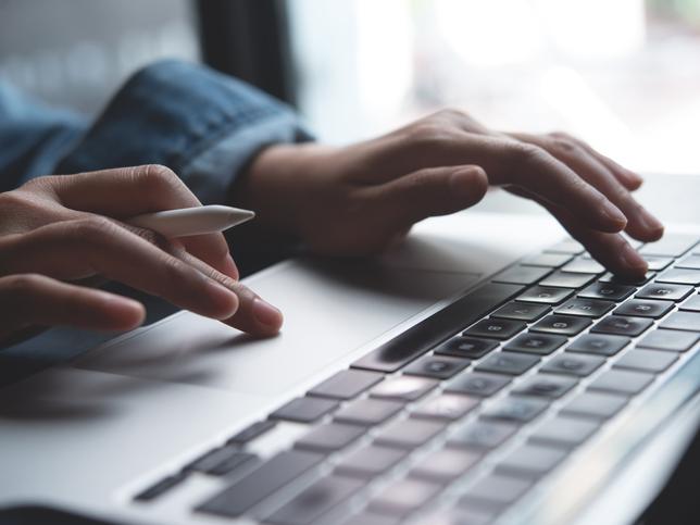 Hands type at a laptop keyboard