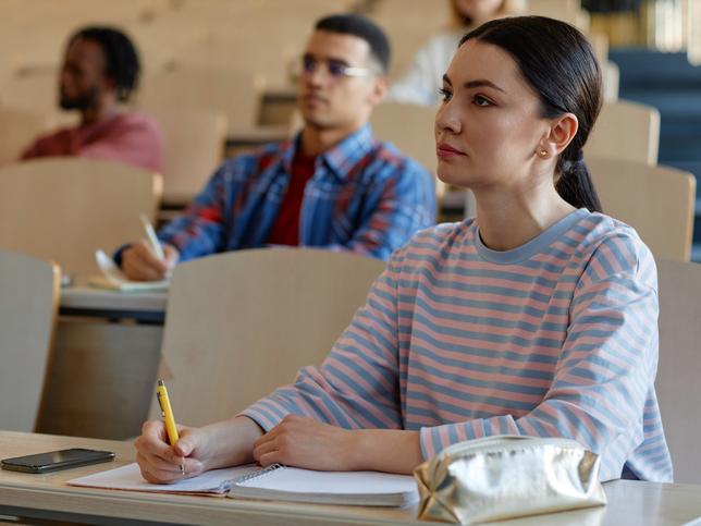 A woman sits in a lecture theatre