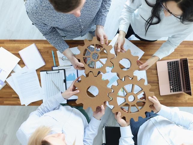 Office workers hold cogs between