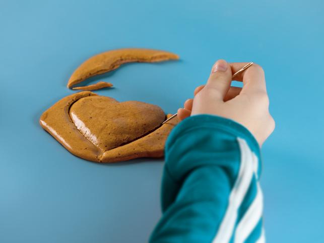 A hand carves out a heart from South Korean delicacy dalgona candy