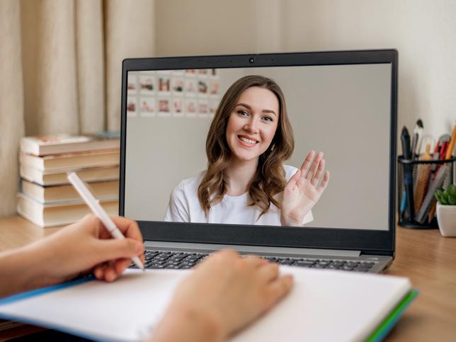 A young woman presents on a screen as someone takes notes