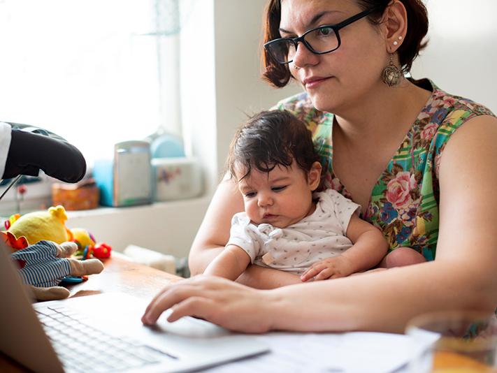 working mother at laptop with toddler