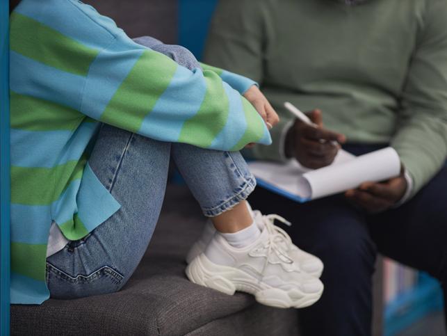 A student hugs her knees while talking 