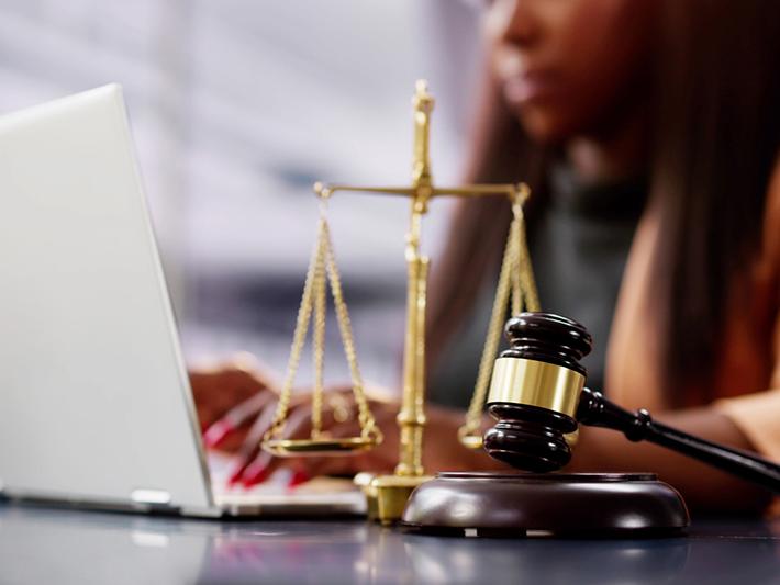 black woman at laptop with scales and gavel, law studies