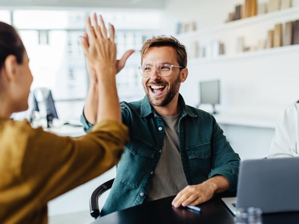 Business people high five each other in the workplace