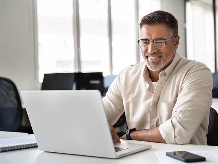 Middle-aged man smiling at laptop