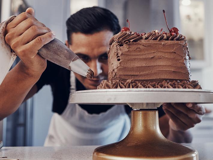 Man putting icing on a chocolate cake