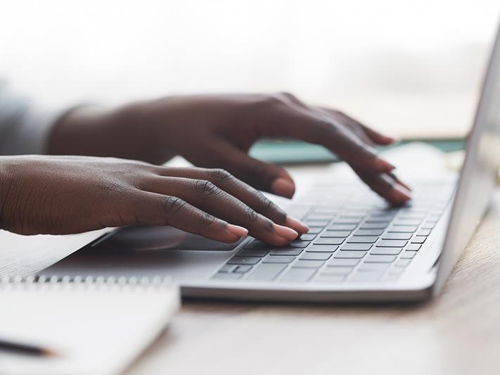 Hands of black woman typing on laptop