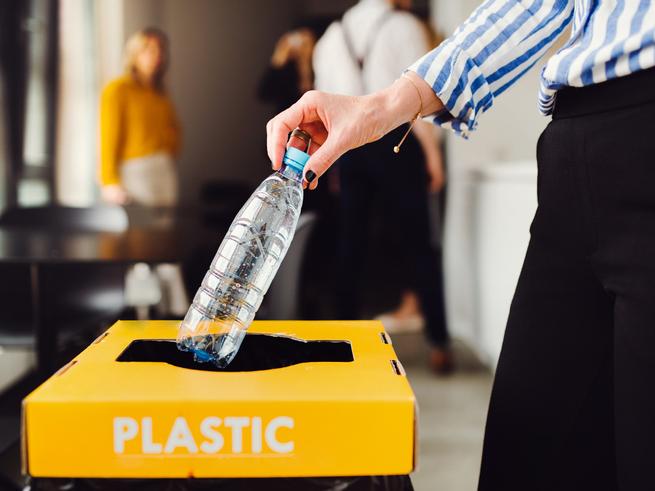 A plastic bottle is placed in a recycling bin