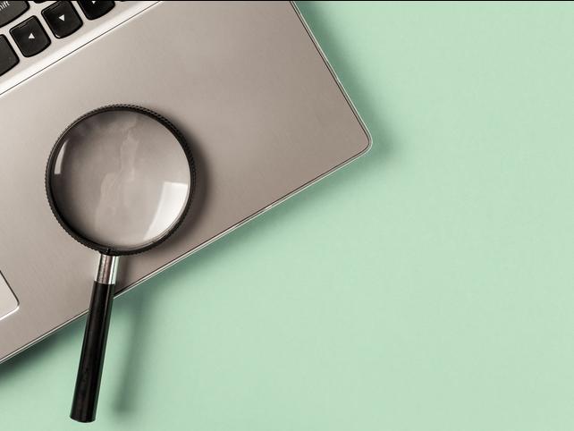 A magnifying glass sits on a laptop