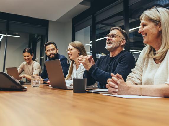 People laugh round a boardroom table