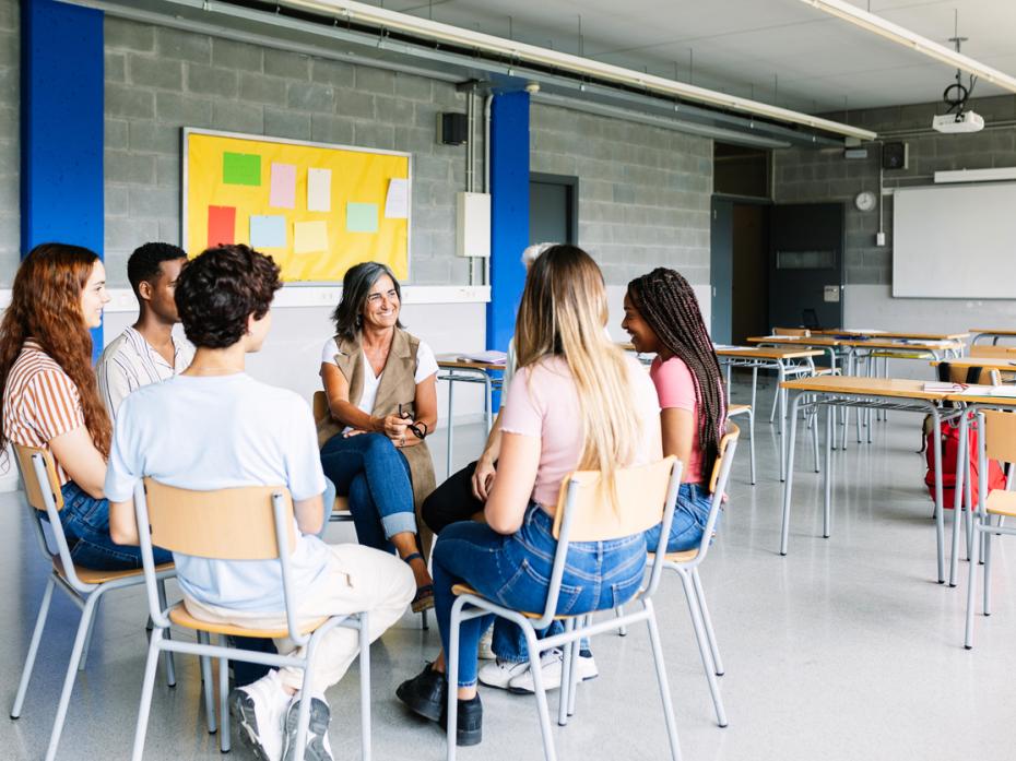 A group of students sitting in a circle while a teacher addresses them