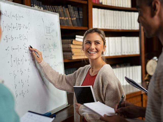 A young student laughs and writes on a whiteboard