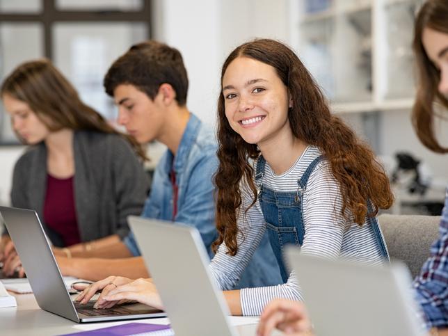 A young woman uses a laptop happily