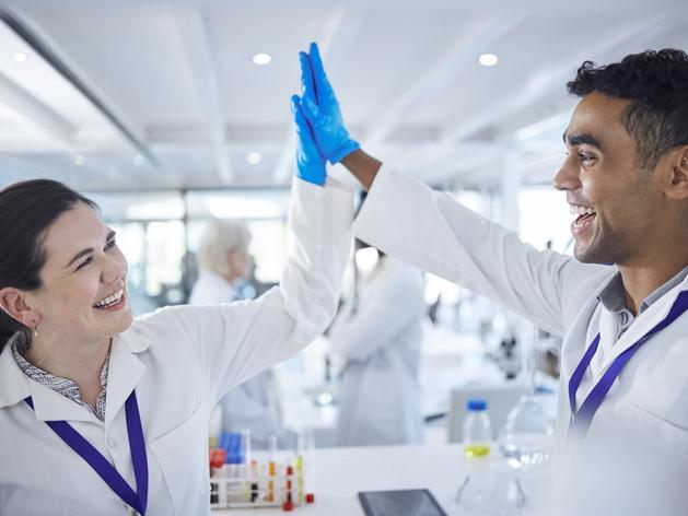 Two researchers in white coats high five