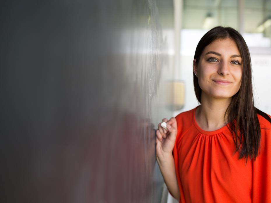 A teacher standing next to a blackboard