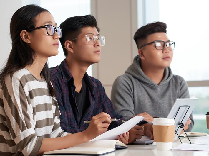 Three Asian university students in a classroom