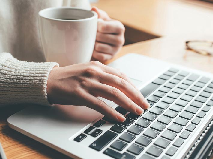 Woman working at laptop with coffee