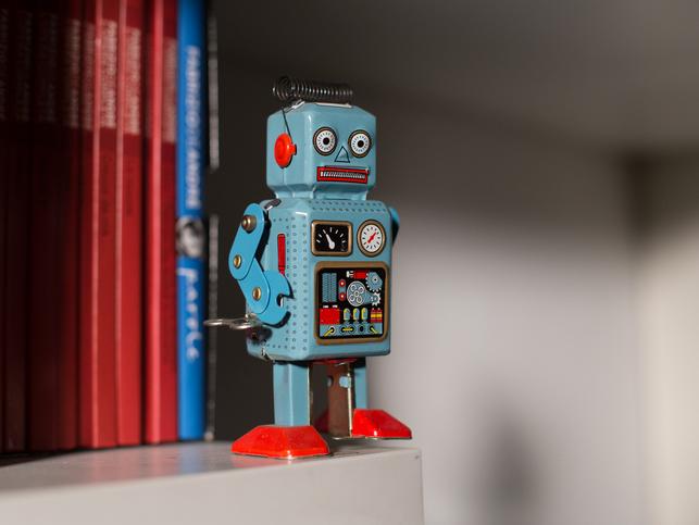 A toy robot stands on a book shelf