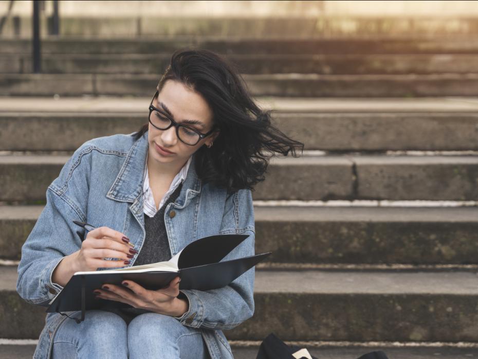 A woman writing in a journal on some steps