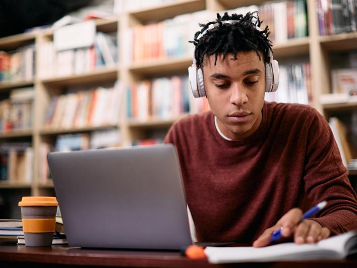 Young black student in headphones at laptop