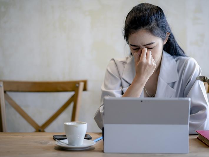 Young Asian woman looking tired at laptop