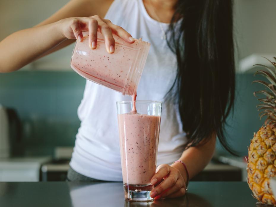 A woman pouring a smoothie into a glass