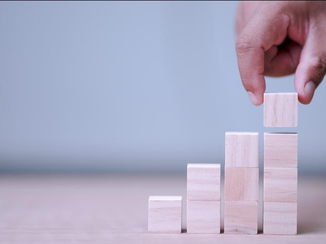 A hand places a wooden block atop three others
