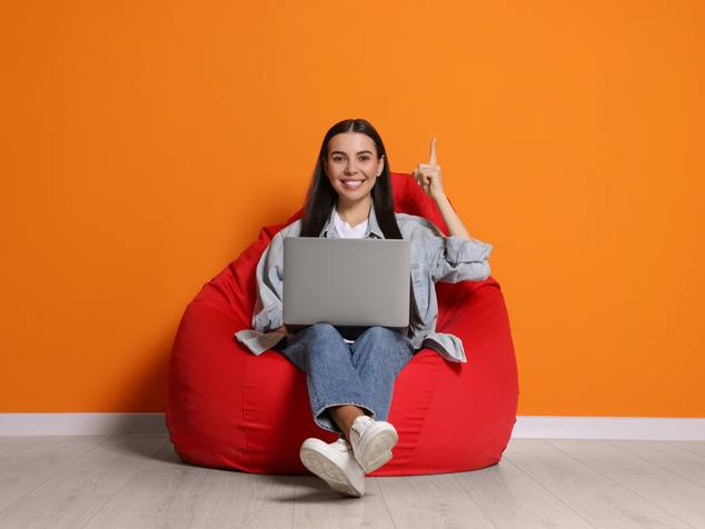 A woman sits in a beanbag chair with a laptop