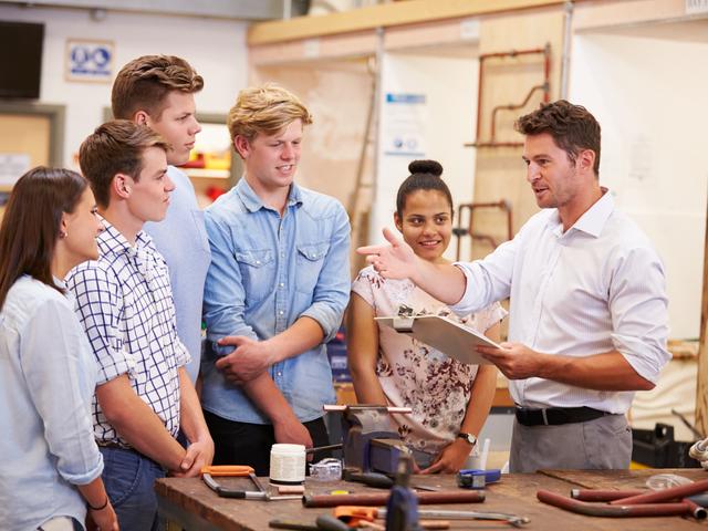 A tutor talks to apprenticeships in a carpentry workshop