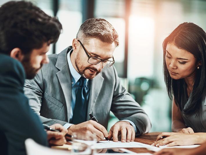 Three people looking at a page in a meeting