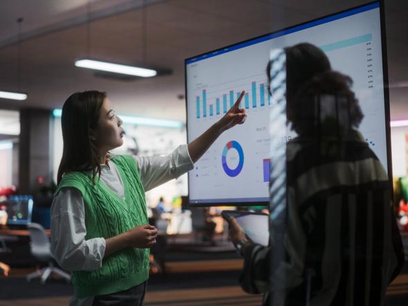 Two employees consider a screen filled with data