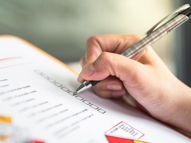 A hand ticks off boxes on a paper form