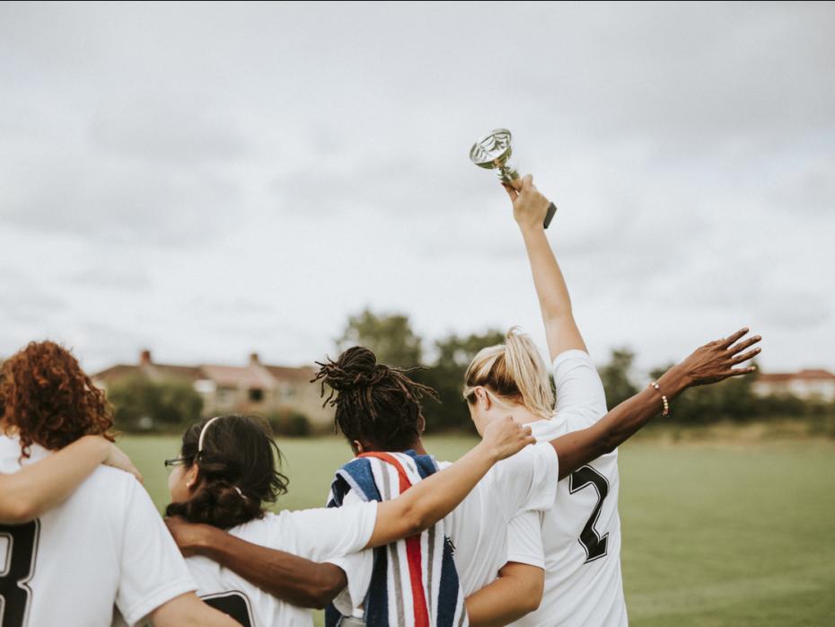 A women's sports team from behind holding a trophy